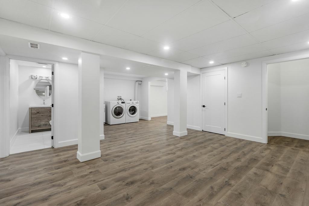 Finished basement with vinyl plank flooring and a laundry area