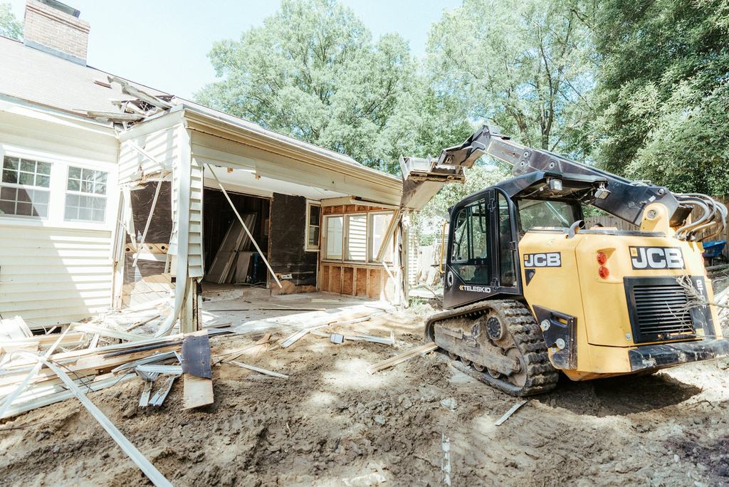 Compact track loader beside a house during a renovation