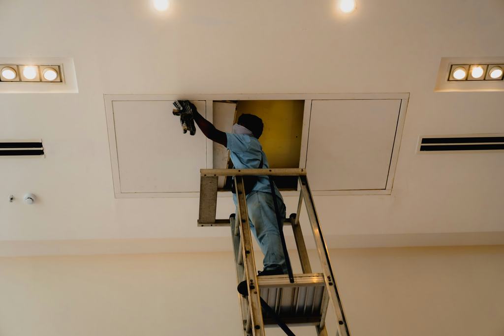 Worker on a ladder at a ceiling access panel