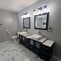 Bathroom with a double vanity, black-framed mirrors and marble-look tile floor