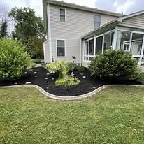 Curved mulch bed with edging along the side of the house