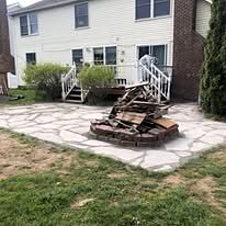 Flagstone patio with a fire pit area behind a house