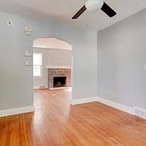 View through an archway to the fireplace room, with refinished hardwood floors