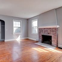 Brick fireplace and refinished hardwood floor in a freshly painted room