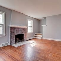 Living room with a brick fireplace, fresh gray paint and refinished hardwood floor